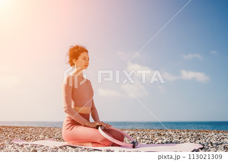 Woman sea pilates. Sporty happy middle aged woman practicing fitness on beach near sea, smiling active female training with ring on yoga mat outside, enjoying healthy lifestyle, harmony and meditation 113021309