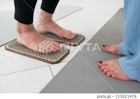 Caucasian woman stands on sadhu boards with therapist support. 113021478
