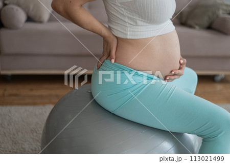 Caucasian pregnant woman suffers from belly pain. Fitball training during pregnancy.  113021499