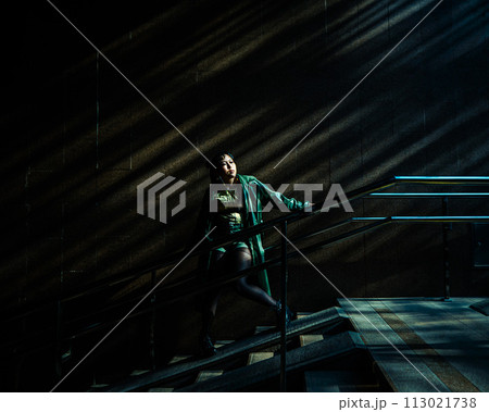 Portrait of a young Asian woman posing in the subway near the stairs.  113021738