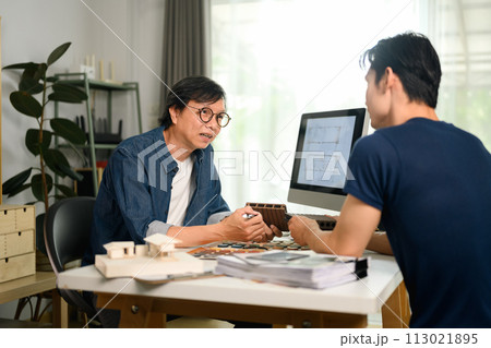 Professional interior designer discussing home renovation project with his client in office Professional interior designer discussing home renovation project with his client in office 113021895