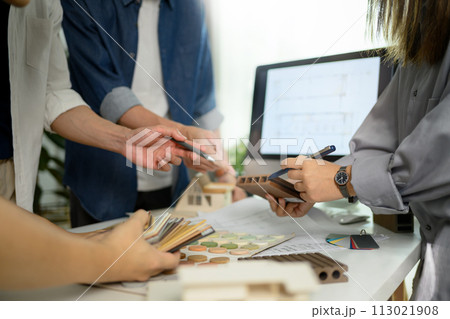 Group of designers of interior choosing material samples, working together at creative office 113021908