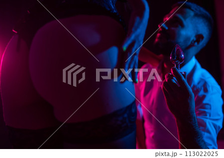 Bearded caucasian man holding an anal plug. Close-up of female buttocks in underwear. Sexual preferences of the couple. Bearded caucasian man holding an anal plug. Close-up of female buttocks in underwear. Sexual preferences of the couple. 113022025