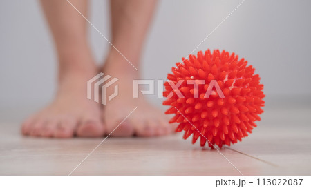 Close-up of a woman's foot on a massage ball with spikes. Close-up of a woman's foot on a massage ball with spikes. 113022087