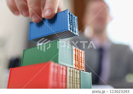 Business man arranging stack of freight containers on his table in office. 113023265