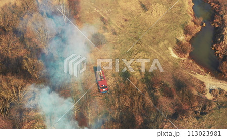 Aerial View. Spring Dry Grass Burns During Drought Hot Weather. Bush Fire And Smoke. Fire Engine, Fire Truck On Firefighting Operation. Wild Open Fire Destroys Grass. Ecological Problem Air Pollution 113023981