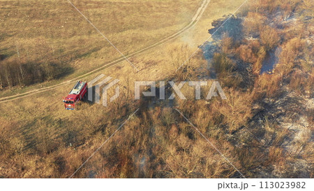 Aerial View. Spring Dry Grass Burns During Drought Hot Weather. Bush Fire And Smoke. Fire Engine, Fire Truck On Firefighting Operation. Wild Open Fire Destroys Grass. Ecological Problem Air Pollution Aerial View. Spring Dry Grass Burns During Drought Hot Weather. Bush Fire And Smoke. Fire Engine, Fire Truck On Firefighting Operation. Wild Open Fire Destroys Grass. Ecological Problem Air Pollution 113023982