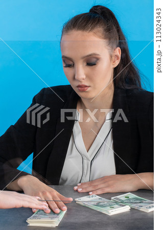 A bank teller accepts money from a client who transfers the cash to be paid into a bank account. A bank teller accepts money from a client who transfers the cash to be paid into a bank account. 113024343
