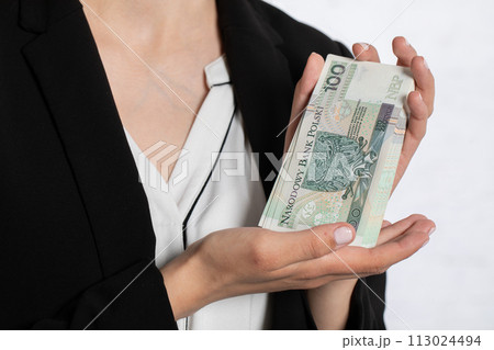 The woman is showing a large bundle of banknotes, holding gently in her hands. 113024494