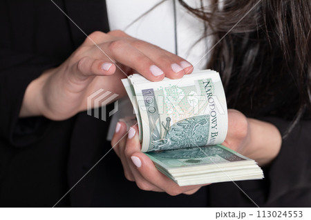 The woman is counting exactly one hundred zlotys paper banknotes. 113024553
