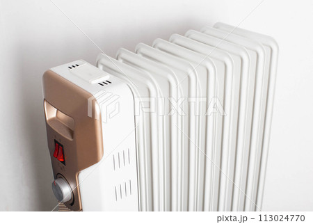 Modern electric oil heater on a white background. Heating the room. Heating season in apartments, close-up 113024770