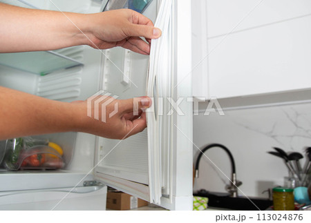 Torn and damaged sealing gum on the refrigerator door. Replacing the old sealing rubber with a new one 113024876