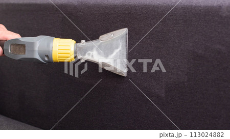 Cleaning the sofa with a special washing vacuum cleaner from dirt. Dry cleaning of sofas and upholstered furniture, close-up. Copy space for text 113024882