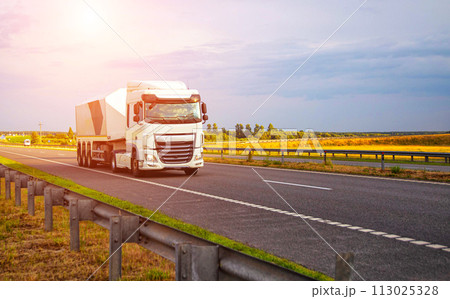 A new modern semi-trailer glass truck transports fragile cargo in the form of glass and mirrors along the highway against the backdrop of sunset. Copy space for text 113025328