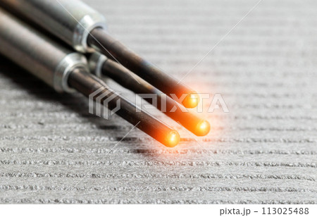 Serviceable modern ceramic glow plugs on a gray background. Orange glow, heating element. Pre-heating of a diesel engine, close-up Serviceable modern ceramic glow plugs on a gray background. Orange glow, heating element. Pre-heating of a diesel engine, close-up 113025488