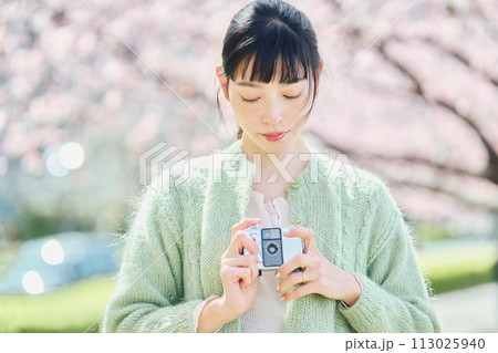 桜の写真を撮る女性 113025940