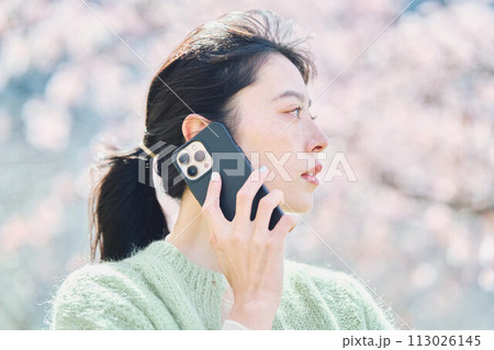 桜の下スマホで通話する女性 113026145