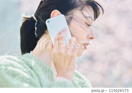 桜の下スマホで通話する女性 113026173