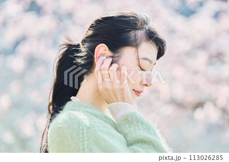 桜の中で音楽を聴く女性 113026285
