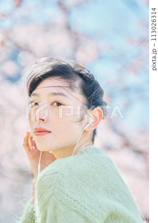 桜の中で音楽を聴く女性 113026314