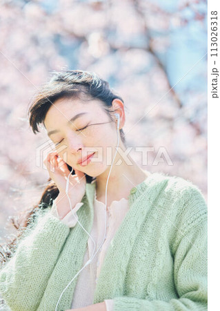桜の中で音楽を聴く女性 113026318