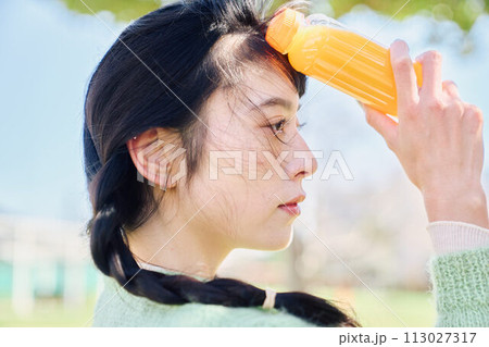 新緑の公園でオレンジジュースを飲む女性 新緑の公園でオレンジジュースを飲む女性 113027317