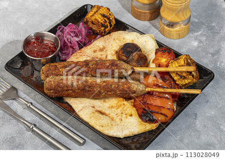 Lamb cutlet with grilled vegetables and lavash. Red onion and corn. Lamb cutlet with grilled vegetables and lavash. Red onion and corn. 113028049