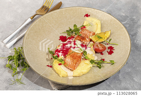 Salmon with mashed potatoes, topped with white sauce and garnished with caviar and pea sprouts. 113028065