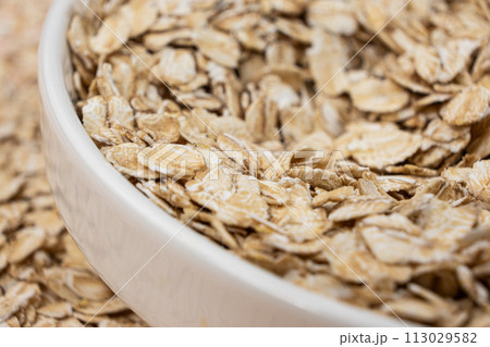 Dry uncooked oat flakes in a plate 113029582