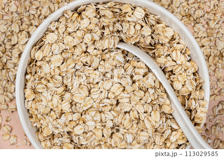 Dry uncooked oat flakes in a plate top view 113029585