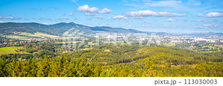 A sweeping vista of Liberec city nestled between rolling hills and Jested ridge under a blue sky dotted with clouds. A sweeping vista of Liberec city nestled between rolling hills and Jested ridge under a blue sky dotted with clouds. 113030003
