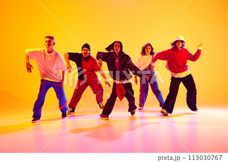 Dancers in dynamic motion, shows contemporary hip-hop dance styles in neon light against gradient colorful studio background. Dancers in dynamic motion, shows contemporary hip-hop dance styles in neon light against gradient colorful studio background. 113030767