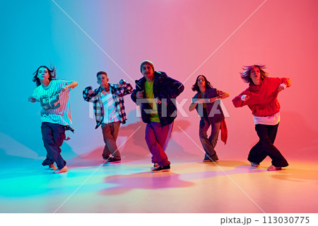 Dance troupe moving energetically in neon light against gradient colorful studio background. Movement. 113030775