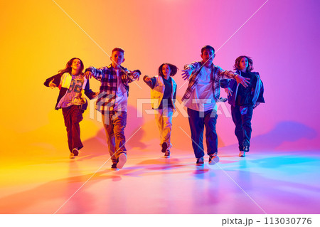 Portrait of youth dance group strides forward in sync in neon light against gradient colorful studio background. Portrait of youth dance group strides forward in sync in neon light against gradient colorful studio background. 113030776