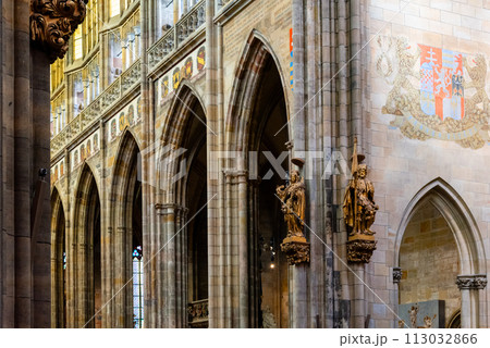 The vaulted ceilings and gothic arches of Saint Vitus Cathedrals interior are showcased, accented by heraldic banners and intricate sculptures. Prague Castle, Prague, Czechia 113032866