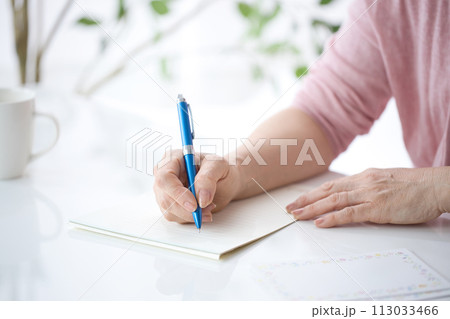 手紙を書くミドル女性の手元 113033466