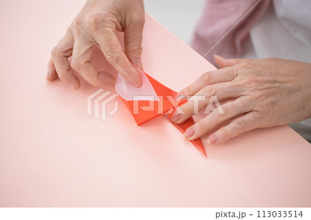 折り紙を折るミドル女性の手元 113033514