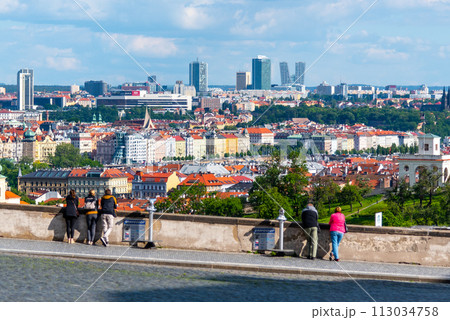 Visitors looking out over the modern skyline of Pankrac set against the historical backdrop of Prague, with lush greenery under a dynamic sky. Prague, Czechia Visitors looking out over the modern skyline of Pankrac set against the historical backdrop of Prague, with lush greenery under a dynamic sky. Prague, Czechia 113034758