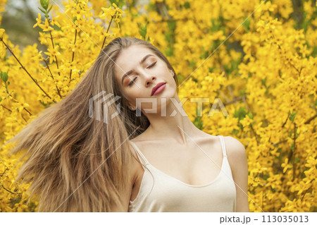 Spring young woman with natural makeup and healthy long brown hair in blossom park outdoors. Spring young woman with natural makeup and healthy long brown hair in blossom park outdoors. 113035013