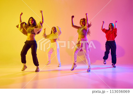 Stylish young women in sport style casual clothe sin motion, dancing hip hop, contemp against gradient background in neon light Stylish young women in sport style casual clothe sin motion, dancing hip hop, contemp against gradient background in neon light 113036069