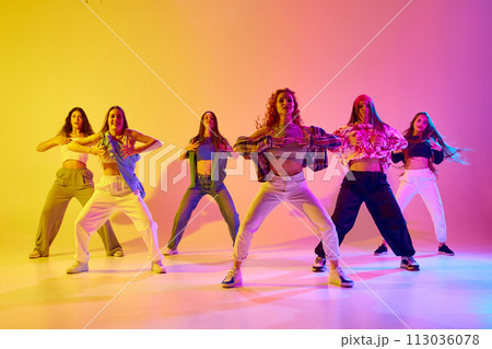 Artistic, talented young women in motion, dancing street style dance against gradient background in neon light 113036078