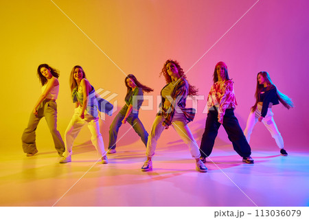 Group of stylish young women dancing contemp, hip hop dance in casual clothes against gradient background in neon light 113036079