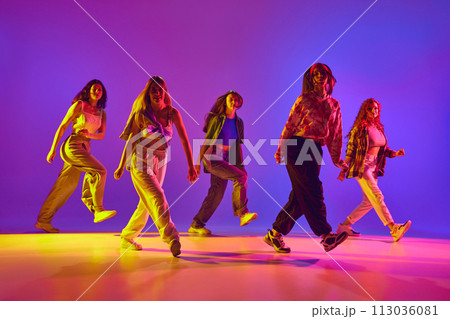 Dynamic image of young talented women in casual clothes in motion, dancing street style dance against gradient background in neon light 113036081