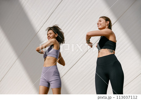 Young sportswomen in tracksuit are stretching outdoor and preparing to jogging. Healthy life concept 113037112