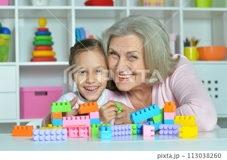 Cute girl and grandmother playing with colorful plastic blocks 113038260