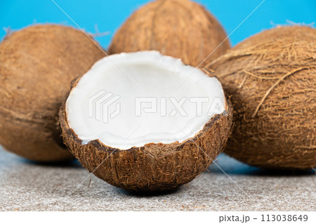 Whole coconuts and half a coconut on a blue and gray background close-up Whole coconuts and half a coconut on a blue and gray background close-up 113038649