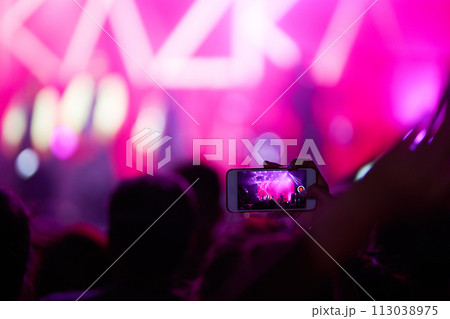 Hand with a phone records live music festival. People taking photographs with smart phone during concert. 113038975