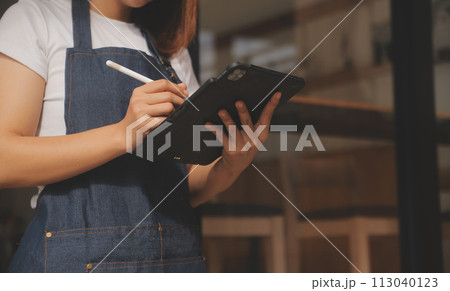 Startup successful small business owner sme beauty girl stand with tablet smartphone in coffee shop restaurant. Portrait of asian tan woman barista cafe owner. SME entrepreneur seller business concept Startup successful small business owner sme beauty girl stand with tablet smartphone in coffee shop restaurant. Portrait of asian tan woman barista cafe owner. SME entrepreneur seller business concept 113040123