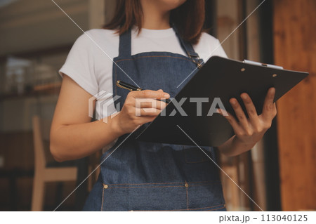 Startup successful small business owner sme beauty girl stand with tablet smartphone in coffee shop restaurant. Portrait of asian tan woman barista cafe owner. SME entrepreneur seller business concept 113040125