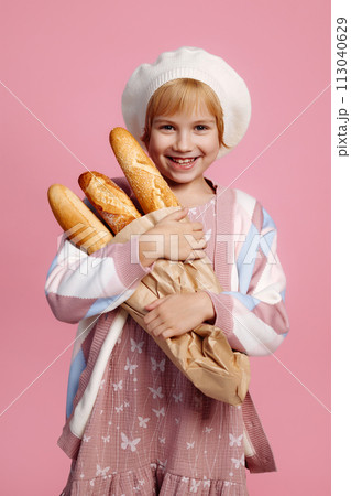 Joyful girl jumping with a bag of bread on a pink background 113040629